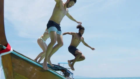 Young group of multi ethnic friends jumping off long tail boat to go swimming. L 스톡 동영상 201094108