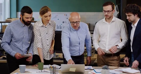 Young group of office workers leaning on a table with documents, charts Stock Footage 82446199