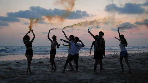 Young group playing firework and smoke on beach with sunset background. Stock Footage 184284896