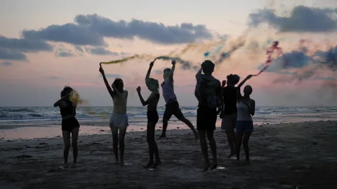 Young group playing firework and smoke on beach with sunset background. Stock Footage 184288605