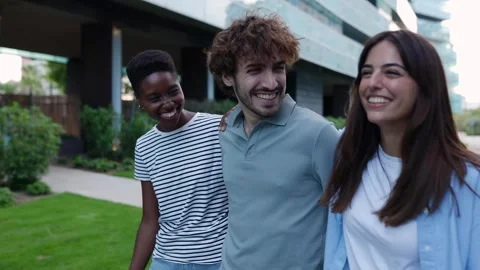Young group of three diverse friends hugging each other while laughing outdoor Stock Footage 310780562
