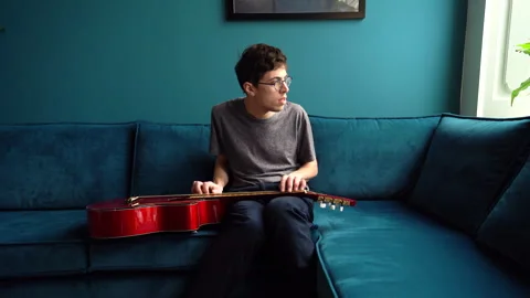 Young Guitarist Staring through a Window whilst playing Guitar Stock Footage 274188680