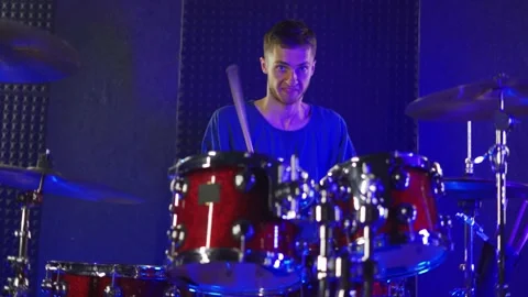 A young guy actively plays the drums in the studio Stock Footage 200229125