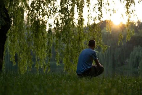 Young guy alone with thoughts on the lake. Concept: sunset, tranquility Foto stock