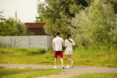 A young guy and his girlfriend are walking in the park along the lake shore.. Stock Photos