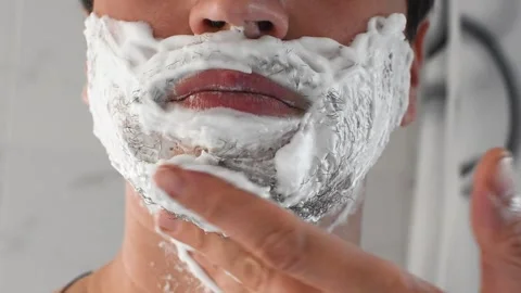 Young guy applying shaving foam. A man shaves his beard, close-up. Stock Footage 273788115