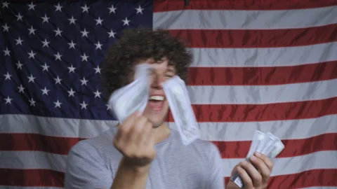 Young guy in background of flag of America throws paper bills with image of Stock Footage 143151845