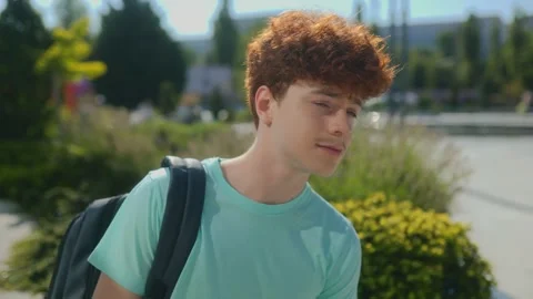 Young guy with backpack chills solo in a sunny city plaza Stock Footage 313471032