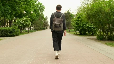 A young guy with a backpack on his back walks through the spring city. Stock Footage 279739473