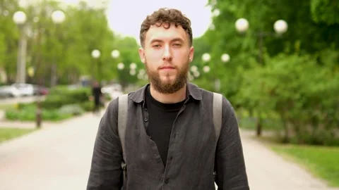 A young guy with a backpack on his back walks through the spring city. Stock Footage 279740382
