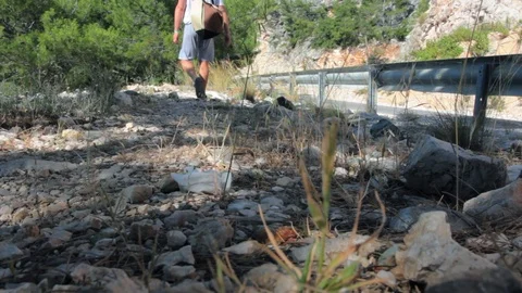 Young guy with a backpack on his shoulder, goes along a rocky mountain path Stock Footage 111668832