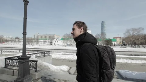 Young guy with backpack walks in the city on boardwalk Stock Footage 91686542