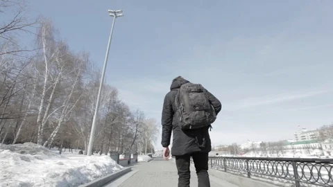Young guy with backpack walks in the city on boardwalk, throwing plastic garbage Stock Footage 91686543