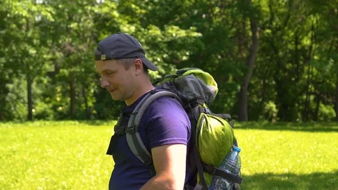 Young guy with a backpack walks in the park, day Stock Footage 109929619