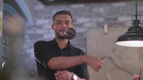 Young guy bartender juggles with a shaker prepares for friends a beautiful and Stock-Footage 96590500