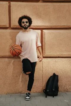 Young guy with a beard and afro hairstyle with basketball ball Foto stock
