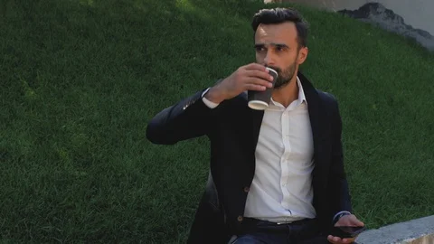 Young guy with a beard in a classic suit drinks coffee from a disposable cup Stock Footage 113903786