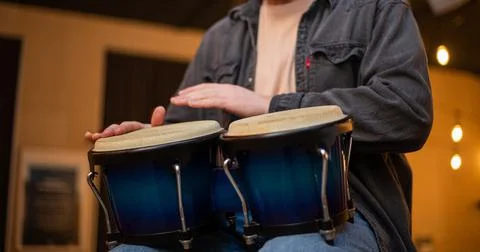 A young guy with a beard plays percussion bongos Stock Photos