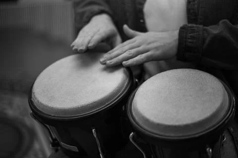 A young guy with a beard plays percussion bongos Stock Photos