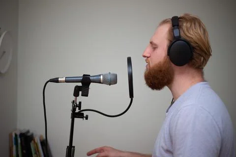 A young guy with a beard sings into a studio microphone with a pop filter Stock Photos
