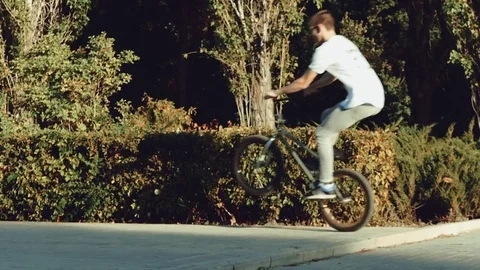 Young guy on a bike-tree doing jumping at sunset in the park. Stock Footage 82142810