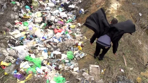 A young guy in a black coat is jumping among the garbage dump Stock Footage 274695277