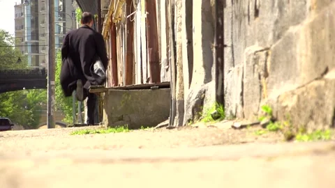 A young guy in a black coat runs along the asphalt Stock Footage 274694599