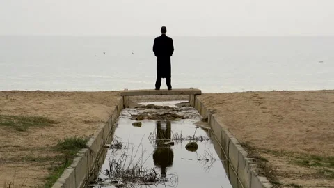 A young guy in a black coat stands on a small bridge Stock Footage 274694659