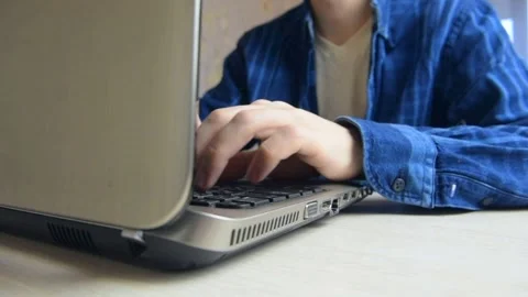 A young guy in a blue checked shirt is typing on a keyboard Stock Footage 146797759