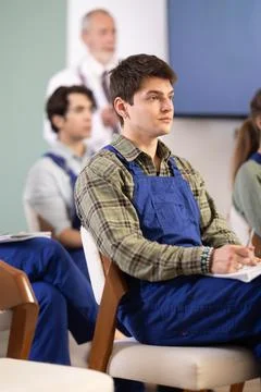 Young guy in blue overalls watching presentation with a doctor standing in Stock Photos