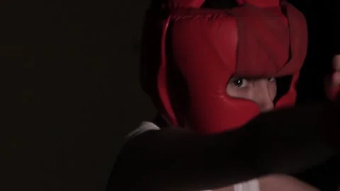 Young guy boxer practices punches in a dark room. Boxing protective helmet and h Stock Footage 201100525
