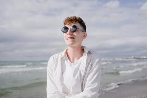 A young guy with braces on his teeth, curly hair and round sunglasses on his  Stock Photos