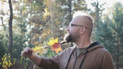 Young guy with braided leaves in his beard, a scythe on his chin 스톡 동영상 96881681