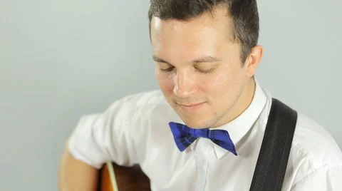 Young guy in a bright blue pants playing a guitar in the studio on a white Stock Footage 49841887
