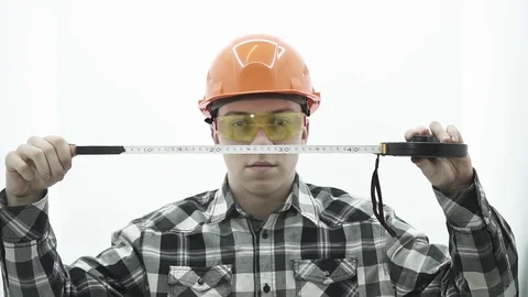 Young guy in a builder costume unwinding a tape measure Stock Footage 107008784