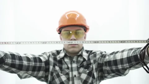 Young guy in a builder costume unwinding a tape measure Video stock 107008792