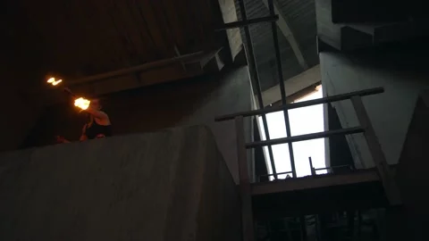 Young guy with burning staff doing fire show on concrete background under road 库存影片 194370700