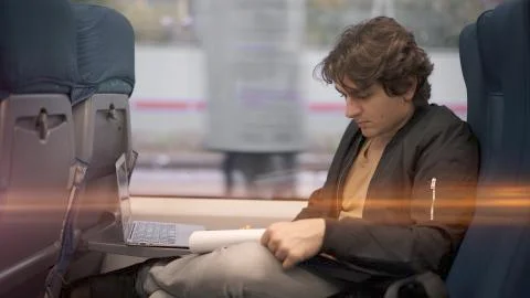 Young guy busy making notes in train, alone young man in a suburban train Stock Photos
