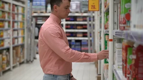 Young guy buys juice in a store or supermarket. Stockbeeldmateriaal 80505801