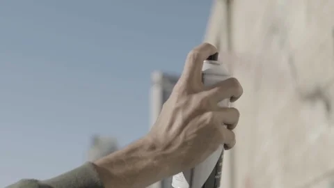 A young guy with a can of paint draws graffiti on the wall. One hand close-up Stock Footage 93727029
