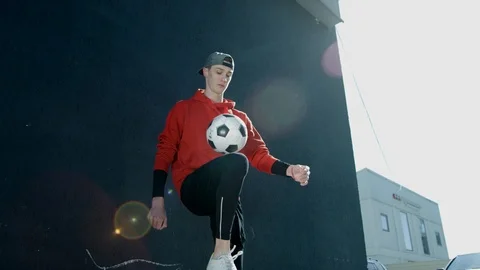 A young guy in a cap throws a soccer ball with his knee. Street football. Stock Footage 114131997