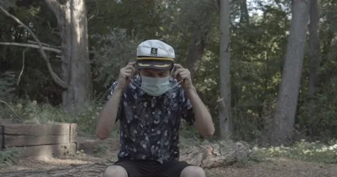 Young guy in captains hat putting on a surgical mask Stock Footage 136737717