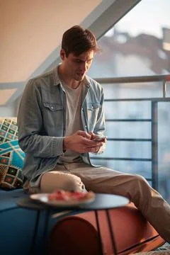 A young guy chatting on the smartphone while resting at home. Man, home, leis Stock Photos