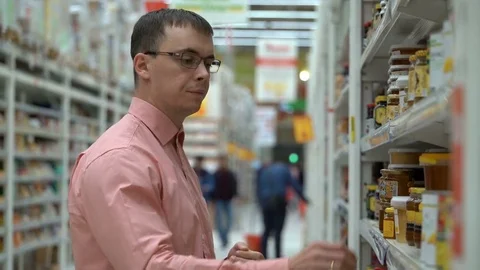 A young guy chooses a honey in a store. Video stock 80359433