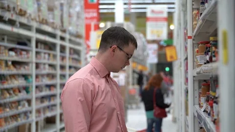 Young guy chooses jam in a store or supermarket. Vídeos de archivo 80359310
