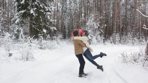 A young guy is circling his beloved girl in the snow forest, they are holding Stock Footage 150254007