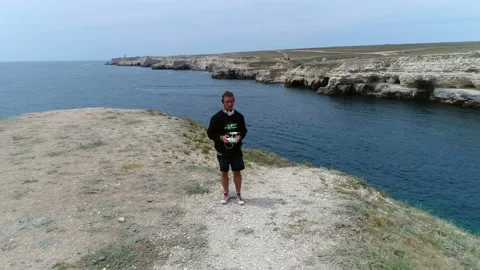 Young guy controls the drone using the remote against the background of the sea Video stock 103084387