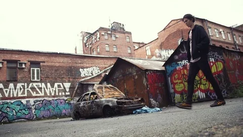 Young guy crouching down near crashed burned car standing outdoors Stock Footage 80008800
