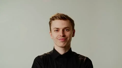 A young guy is cute smiling on camera. A sincere smile of a guy in a black Stock Footage 244836574