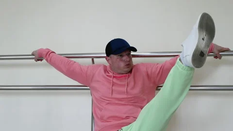 A young guy dancer is warming up near the ballet barre, Do dance leg swings Stock Footage 277913205